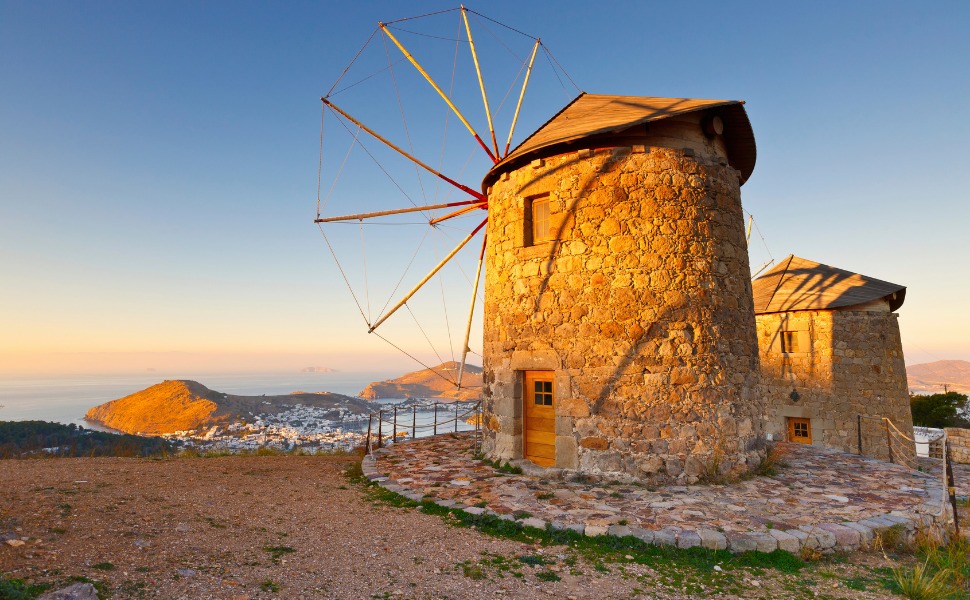Steinerne Windmühlen der Chora im warmen Abendlicht, dahinter Meer und Skala